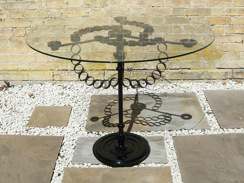 Glass table created from reclaimed steel and found objects